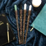 Unique Gifts From The Hidden Hatch. - Licensed Products and Gothic Gifts 30 Four crystal-tipped wooden wands on dark blue velvet with books, candle, and pen nearby.