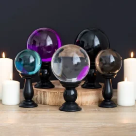 Alternative Homeware Trends to Watch 6 Colorful crystal balls on black stands surrounded by lit white candles on a wooden surface.