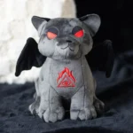 Vampire Cat Plush Toy. How to build Halloween hampers. Gothic gifts for gothic friends A gray cat-gargoyle plush with red eyes, black bat wings, and an embroidered red symbol.