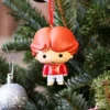 Ron Weasley Christmas Ornament Figurine - Red Sweater Design A Ron Weasley Christmas ornament hanging on a decorated green tree with a silver bauble.