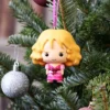 Pink Girl Ornament Plastic Figurine - Festive Christmas Tree Decor A pink-dressed girl ornament hanging on a decorated Christmas tree with glittery baubles.