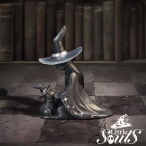 Metal witch figurine with matching bunny companion in a mystical library setting.