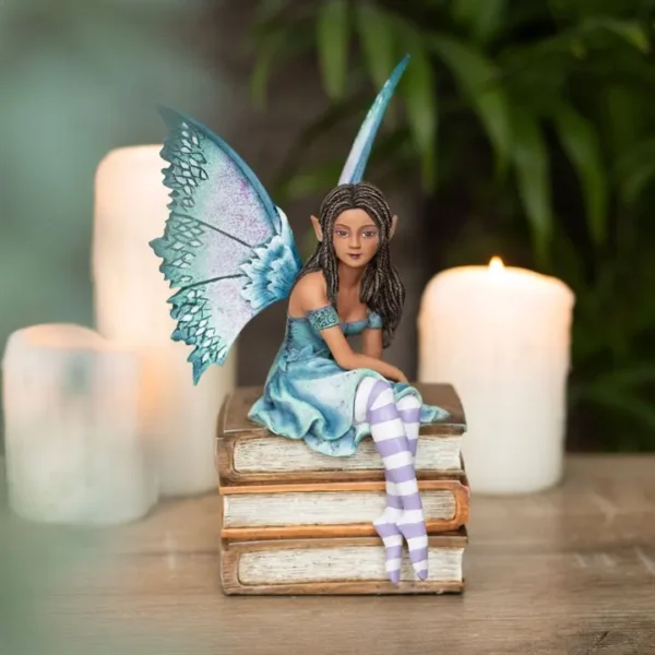 Blue Fairy Figurine Resin Collectible - Iridescent Wings & Books A delicate fairy figurine with blue wings sitting on vintage books surrounded by glowing candles.
