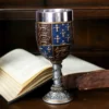 Medieval Goblet Chalice Metal Blue Gold - Fleur-de-Lis Design An ornate blue and gold medieval goblet resting before an open antique book on a wooden table.