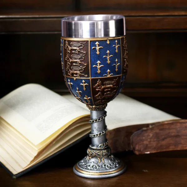 Medieval Goblet Chalice Metal Blue Gold - Fleur-de-Lis Design An ornate blue and gold medieval goblet resting before an open antique book on a wooden table.