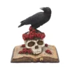 Gothic Raven Skull Resin Sculpture - Black and Red Roses A black raven perched on a skull with red roses atop an open aged book.