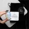 Opalite Crystal Skull Carving Milky White - Iridescent Glow Opalite crystal skull carving with iridescent glow held by hand on black velvet pouch.