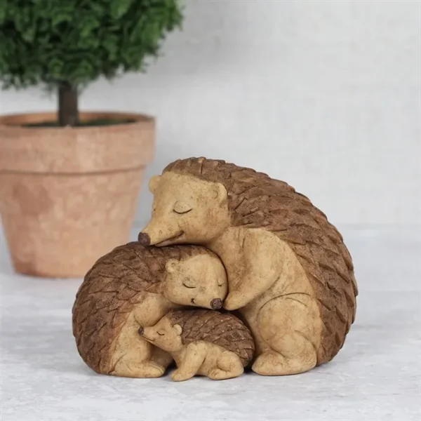 Hedgehog Family Sculpture Carved Wood Brown - Loving Embrace A wooden-style sculpture of three hedgehogs cuddling together beside a small potted green plant.