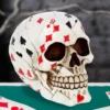 Playing Card Skull Sculpture - Ivory Mosaic on Green Table A human skull sculpture made of playing cards on a green poker table.