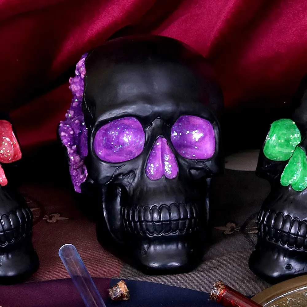 A black decorative skull with glowing purple crystal eyes on red fabric background.
