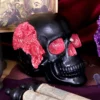 Black Human Skull Sculpture Resin Art - Pink Crystal Geode Detail A black decorative skull with pink crystal geode details on a dark, artistic background.