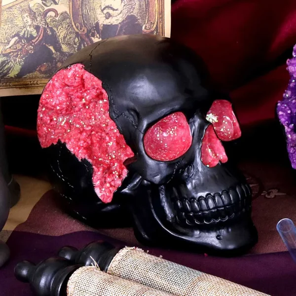 Black Human Skull Sculpture Resin Art - Pink Crystal Geode Detail A black decorative skull with pink crystal geode details on a dark, artistic background.