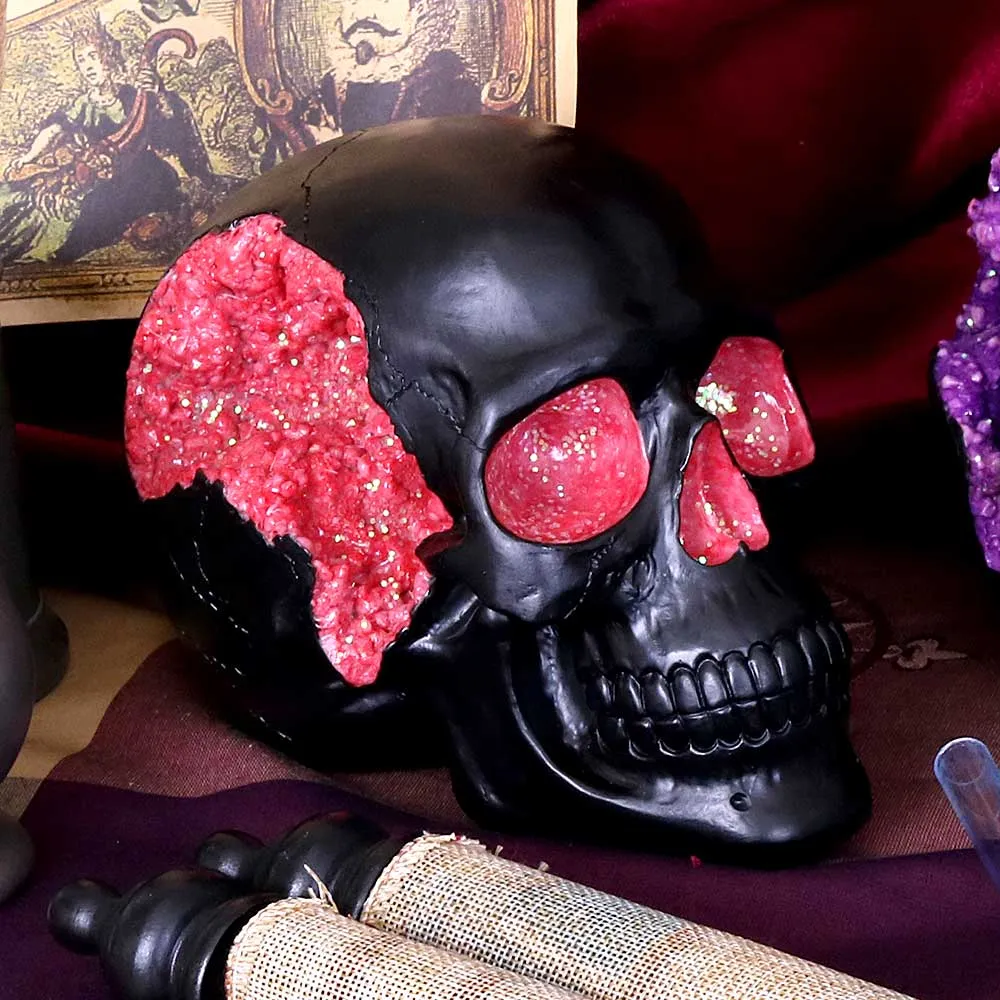 A black decorative skull with pink crystal geode details on a dark, artistic background.