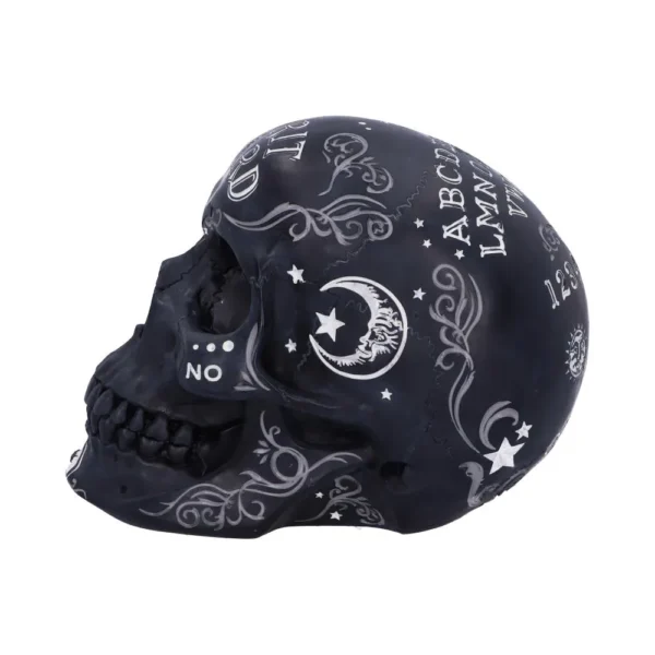 Black decorative skull with white Ouija board letters, crescent moon, and ornate mystical patterns.