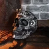 Black Ceramic Spirit Board Skull - Occult Design Decor A black decorative spirit board skull beside an embossed leather book on a wooden surface.