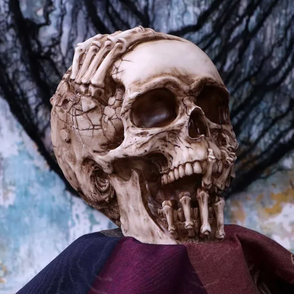 Haunting Skull Sculpture Resin Bone White - Grasping Skeletal Hands A detailed skull sculpture with skeletal hands grasping it against a dark draped background.