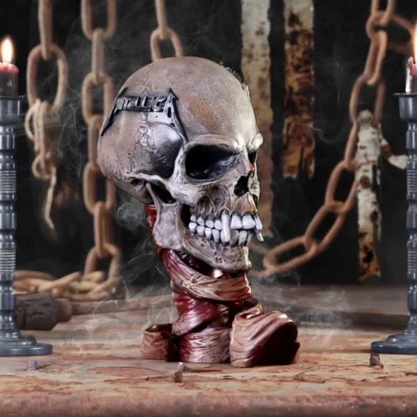 Metallica Skull Sculpture Resin Gothic Brown - Candles And Chains A gothic skull sculpture with Metallica logo, lit candles, and rusted chains in smoky darkness.