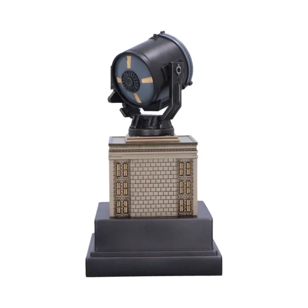 A detailed black and gold Bat-Signal spotlight replica on a decorative pedestal display base.