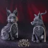 Cult Cuties Resin Dog Figurines Black Cloaked Occult Design Baphomet - Best gifts for collectors. Two black demonic dog figurines with horns and cloaks against a red cosmic background.
