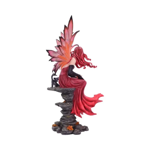 A red-haired fairy figurine with crimson wings sitting gracefully on a rocky base with autumn leaves.