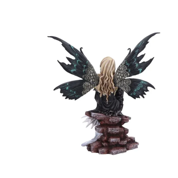 A blonde fairy figurine with black and teal wings sitting gracefully on stacked rocks.
