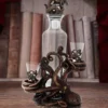 Octopus Glass Decanter Set Bronze Finish - Nautical Tentacle Design A bronze octopus-themed glass decanter set with two shot glasses on a wooden surface.