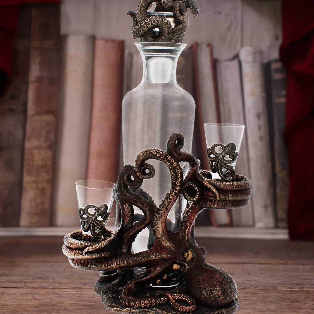 A bronze octopus-themed glass decanter set with two shot glasses on a wooden surface.