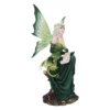 A detailed fairy figurine with green wings sitting on a tree stump beside a small dragon.