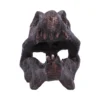 Dinosaur Skull Sculpture Resin Dark Brown With Sharp Teeth Close-up of a dark brown sculpted dinosaur skull with sharp teeth and weathered bone texture.