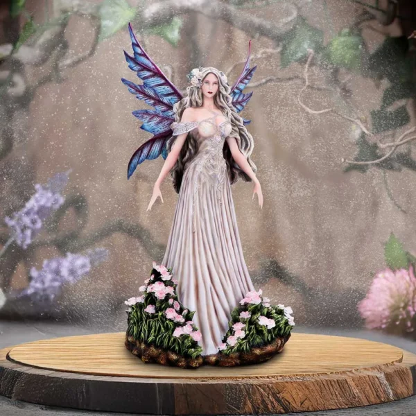 Fairy Figurine Resin Sculpture Blue Iridescent Wings - Floral Base A detailed fairy figurine with iridescent wings standing on a wooden base surrounded by pink flowers.