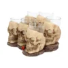 Skull Shot Glass Set Resin Holders Beige - Gothic Bar Decor Six resin skull shot glass holders with clear glass inserts on a dark textured base.