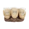 Skull Jaw Shot Glass Set Resin Beige - Gothic Rustic Base Design Four clear shot glasses held in beige skull-jaw shaped holders on a rustic wood-like base.