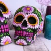 Black Sugar Skull Ceramic Decor - Colorful Floral Design Gothic gifts for gothic friends A colourful floral-decorated black sugar skull on a wooden table with teal and purple candles.