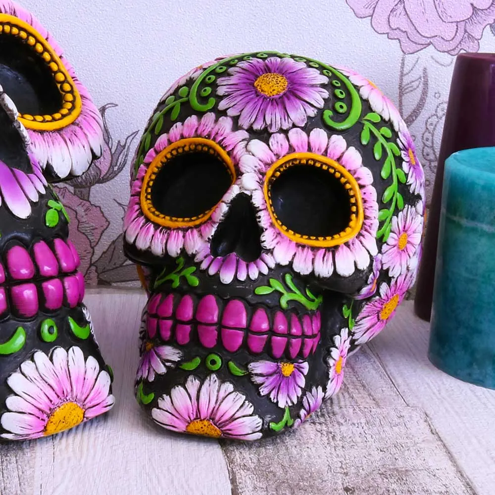 Gothic Friends - What Gothic Gifts Suit Best? 6 Gothic gifts for gothic friends A colourful floral-decorated black sugar skull on a wooden table with teal and purple candles.