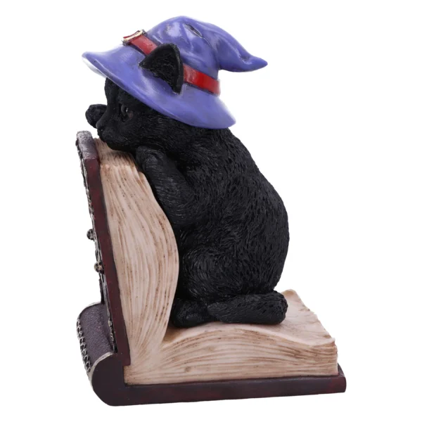 Black cat figurine in a purple wizard hat leaning on an old spellbook The-Hidden-Hatch