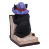 Black Cat Figurine Resin Sculpture Purple Hat on Spellbook Black cat figurine with purple witch hat sitting on open spellbook and small skull. The-Hidden-Hatch