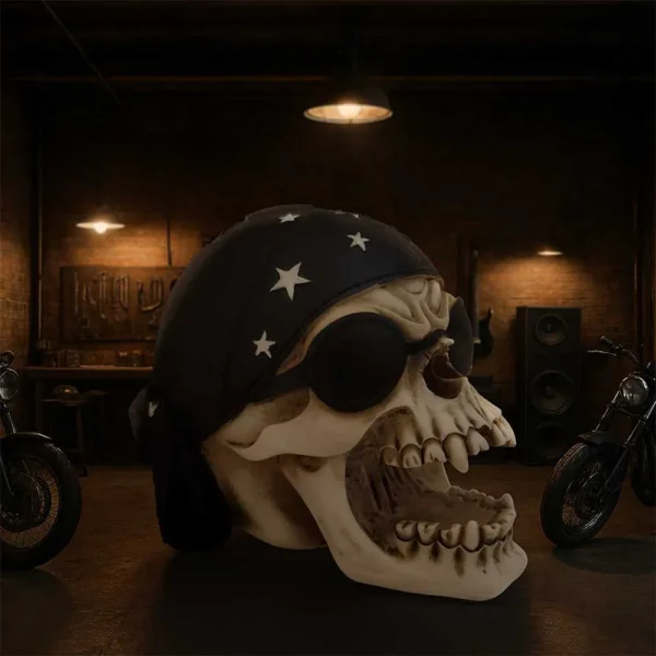 Biker Skull Decor Metal Art Black Finish - Rebellious Design A skull in biker gear with goggles and bandana between motorcycles in a dim garage.